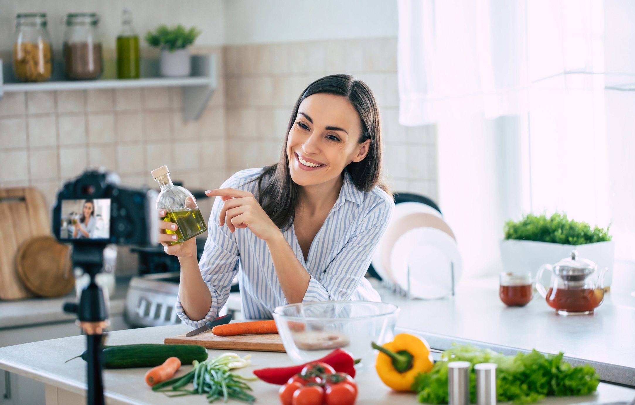 Professional beautiful happy young woman is blogging for her kitchen channel about healthy living in the kitchen